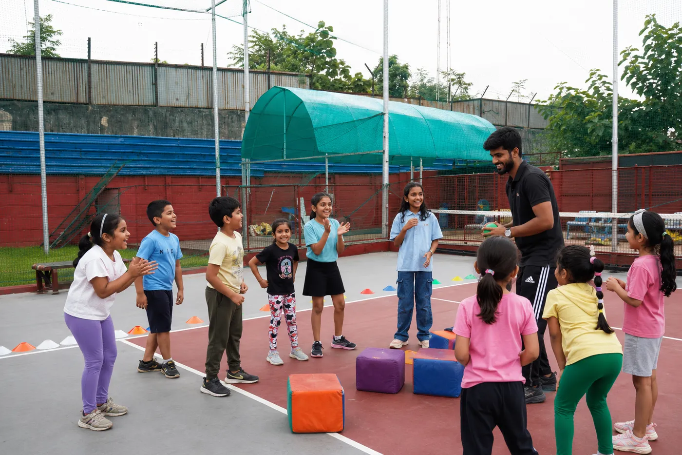 Coach Arsh with a circle of kids at the start of a session, everyone laughing