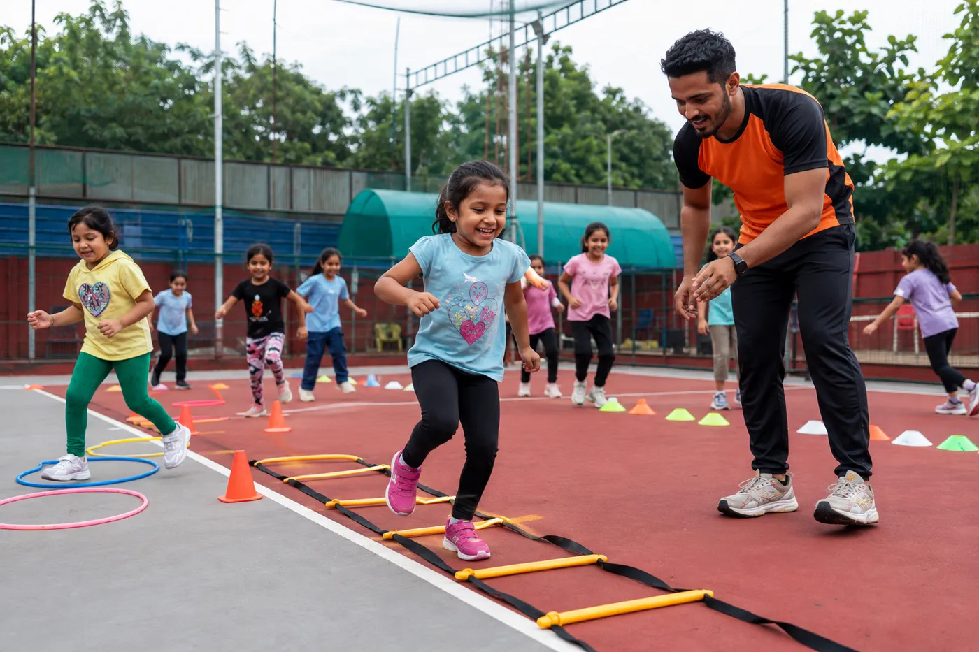 A young girl going through an agility ladder while a coach cheers her on